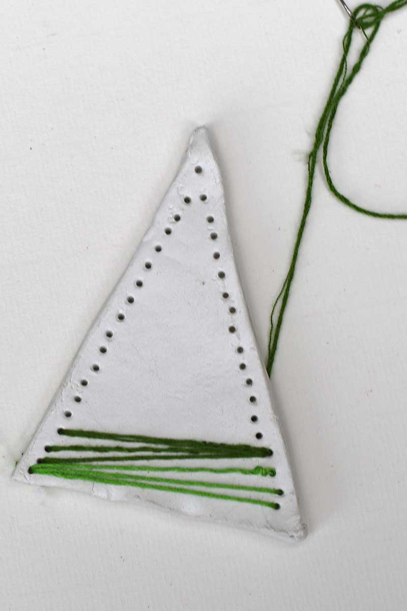 stitching the clay christmas tree ornament with green thread.