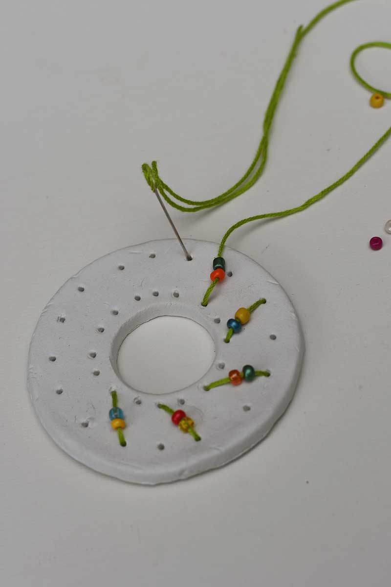 Stitching the clay embroidered wreath with glass sead beads