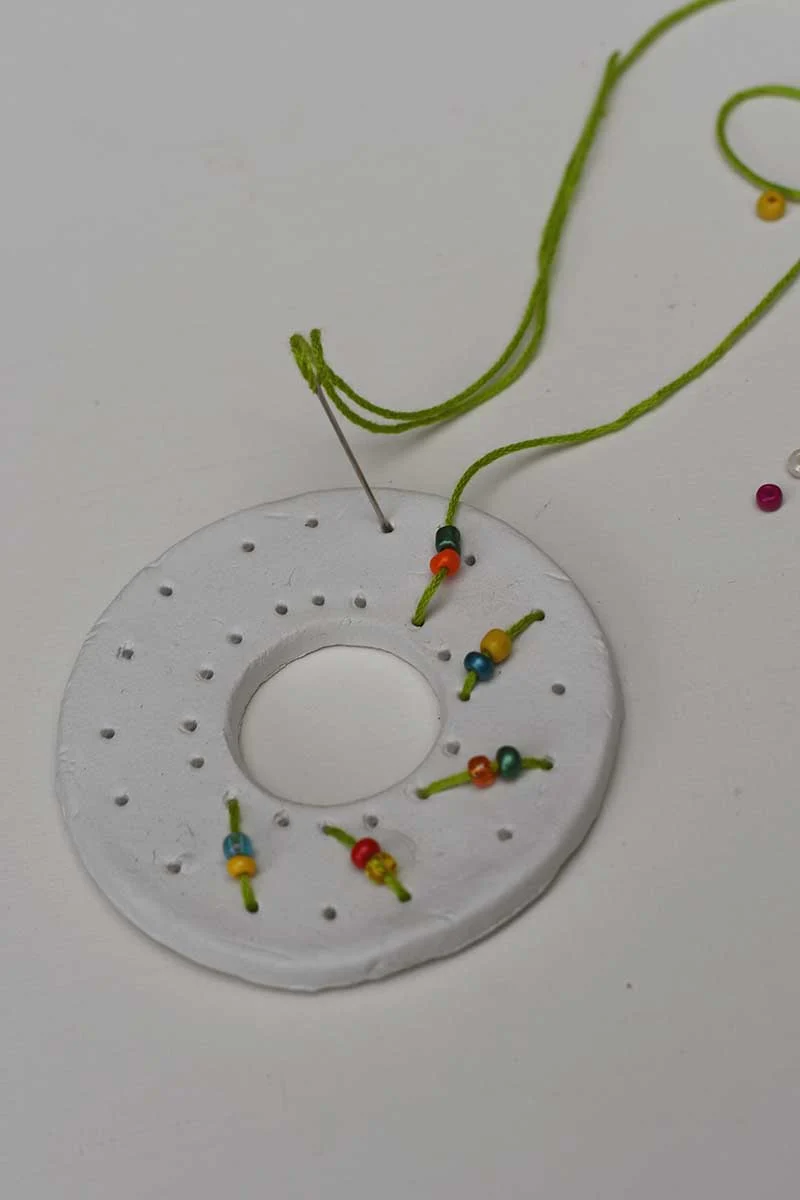 Stitching the clay embroidered wreath with glass sead beads