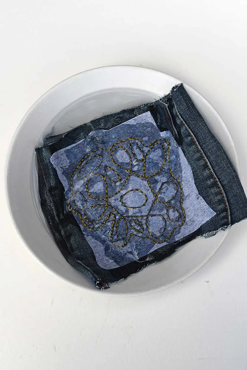 Dissolving embroidery paper in water on denim stitched piece