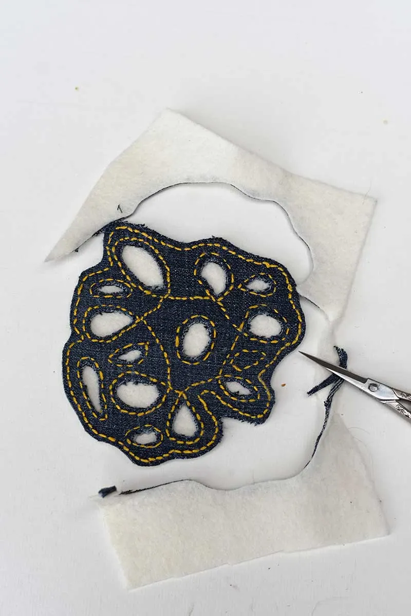 Trimming the denim coasters with scissors cutting away excess felt