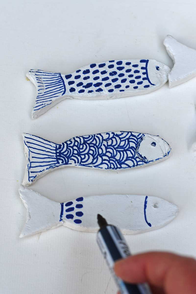 Colouring the clay fish with blue marker pen