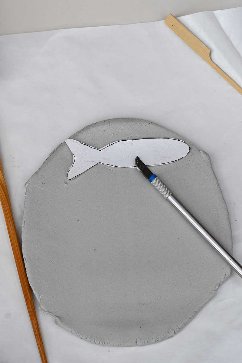 Rolling out air dry clay with fish template