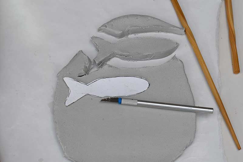 cutting out fish shapes from clay
