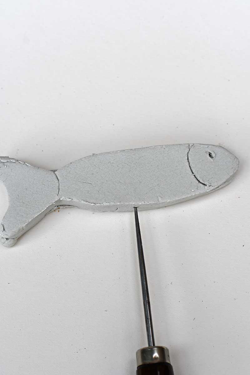 Making a hole into the base of the clay fish